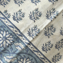 Load image into Gallery viewer, A pale blue and white tablecloth with a floral pattern.