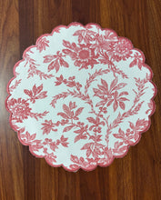 Load image into Gallery viewer, A round pink placemat with a floral pattern and scalloped edges on a wooden surface.