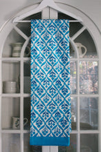 Load image into Gallery viewer, Bright blue and white patterned towel hanging on a white rack in front of a window
